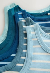 Pile de débardeurs en coton bleu et bleu sarcelle, rayés et unis, sans manches, dans différentes nuances.