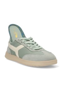 Zapatilla verde claro con parte superior de ante y tejido, acentos crema, cierre de cordones, lengüeta texturizada y suela de goma suave.