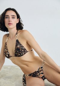 Bikini z leopardskim vzorcem in zlatimi detajli, ki ima trikotno zgornji del in spodnji del s vezanjem ob strani. Gladko blago z leskom in raznolikimi živalskimi motivi.