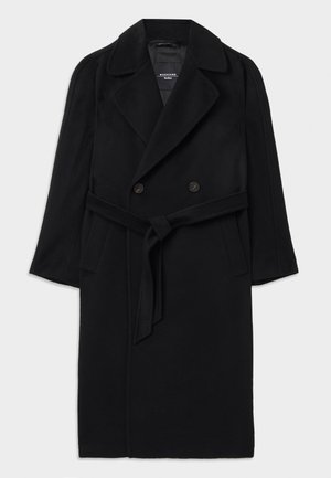 Manteau en laine noir au design croisé, avec un grand col et une taille ceinturée. Il possède des poches latérales et un tissu texturé.