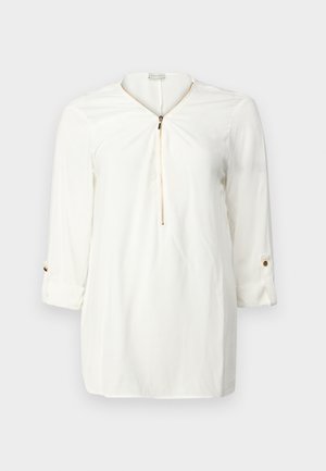 Camicia bianca a maniche lunghe con scollatura con zip, tessuto morbido, dettagli con polsini arrotolati e un accento di bottone dorato.