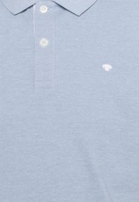 Polo bleu clair texturé avec deux boutons blancs et un petit logo blanc brodé sur la poitrine.