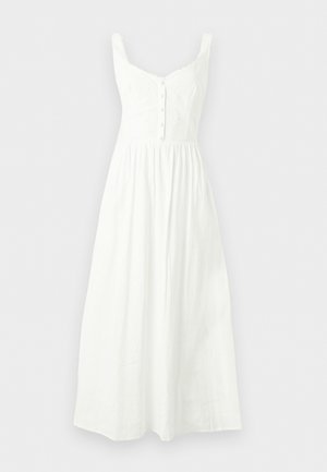 Robe maxi blanche sans manches avec un corsage ajusté à boutons sur le devant et une jupe froncée sur un fond clair uni.