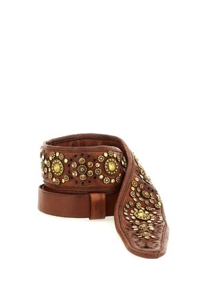 Cintura in pelle marrone decorata con borchie circolari in oro e ottone disposte a motivi floreali, arrotolata su sfondo bianco.