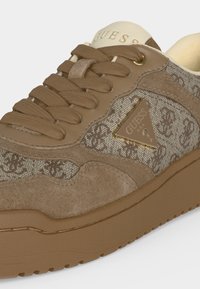 Καφέ sneaker Guess με υφασμάτινο σχέδιο, πάνελ από σουέτ, κορδόνια στο ίδιο χρώμα και χρυσό τριγωνικό λογότυπο στο πλάι.