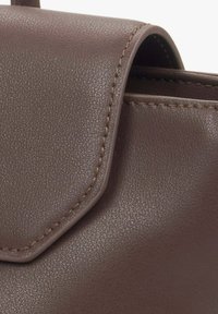 Sac à main en cuir marron avec une surface texturée, doté d'un rabat et de détails de couture contrastants. Design compact, sans accents supplémentaires.