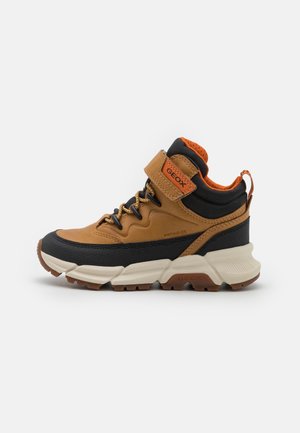 Baskets montantes marron et noir avec une doublure orange, une semelle blanche épaisse, des lacets noirs et une bride Velcro portant l'étiquette Geox.