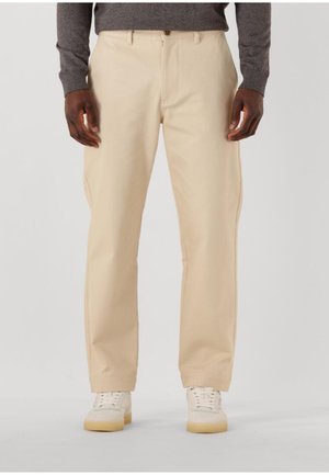 Beiga byxor i bomullsblandning med rak bendesign, knappstängning och sidofickor. Bärs med vita sneakers.