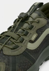 Πράσινα αθλητικά παπούτσια με υφασμάτινο επάνω μέρος με υφή, κομψό σχεδιασμό, ελαστικά κορδόνια και διακριτικό λογότυπο Vans στο πλάι.