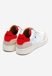 Un par de zapatillas blancas con suelas beige y acentos rojos en el talón, texto negro "NEWLAB" en los talones y cordones blancos sobre un fondo liso.