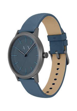 Orologio analogico rotondo con quadrante opaco blu scuro, indici argentati, cassa in metallo grigio e cinturino in pelle blu con lato inferiore beige.