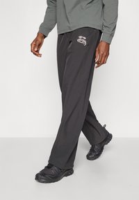 Zwarte, lichte joggerbroek met een losse pasvorm, voorzien van een groot wit logo op de linker dij en subtiele zijzakken.