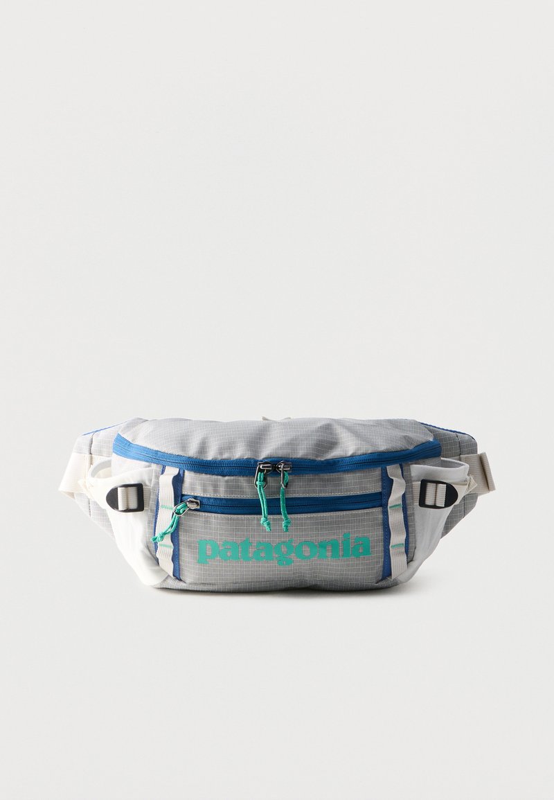 Γκρι και λευκός ιμάντας μέσης Patagonia με δύο θήκες με φερμουάρ, μπλε φερμουάρ, τιρκουάζ λογότυπο και ρυθμιζόμενους μπεζ ιμάντες.