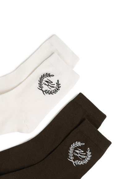 Deux paires de chaussettes mi-hautes, une blanche et une brun foncé, chacune ornée d'une petite couronne de laurier brodée et d'un logo en écriture près du bord-côte.