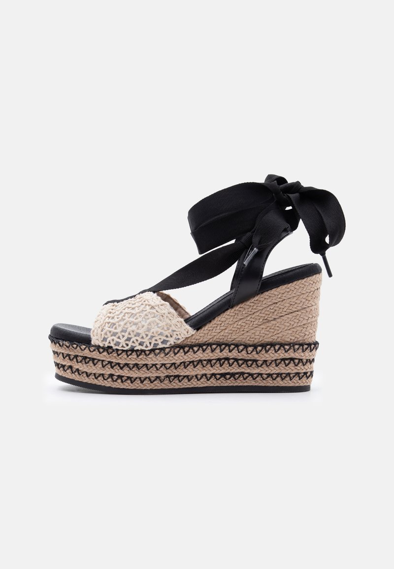 Πλατφόρμα σανδάλι με σφήνα, μαύρο δέσιμο στον αστράγαλο, κρεμ εμπρός λουρί από κροσέ και πλεκτή σόλα από τζούτ με μαύρες ραφές.