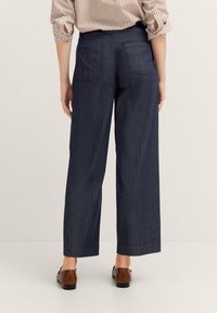 Dunkelblaue weit geschnittene Hosen aus Denim mit glatter Textur, ausgestattet mit zwei Gesäßtaschen und einem einfachen Bunddesign.