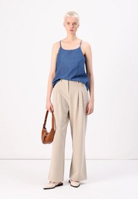 Denim spaghetti strap top, light beige pleated trousers, brown shoulder bag, and cream flats. Simple, tailored silhouette.