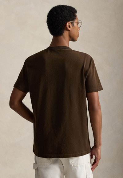 Tricou maro din bumbac cu mâneci scurte, guler rotund și croială lejeră, având o textură fină și cusături subtile în jurul tivului.