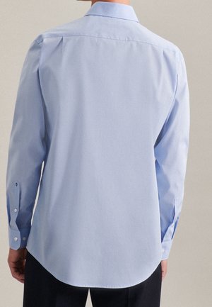 Camisa de manga larga azul claro con cuello estándar, dobladillo redondeado y puños abotonados. Hecha de una tela suave con un patrón liso.