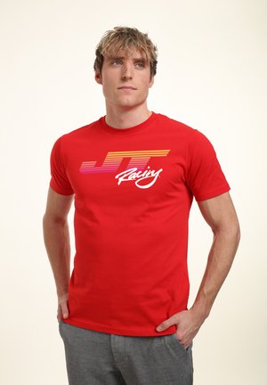 Rød bomulds T-shirt med "JT Racing" logo i hvid og gradient farver. Korte ærmer og crew neck design, båret med grå bukser.