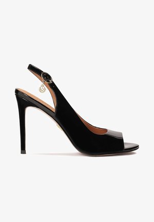 Schwarze Lackleder Slingback-Pumps mit offenem Zehenbereich, geschwungenem Design und dekorativem goldenen Anhänger an der Ferse, glatte Textur.