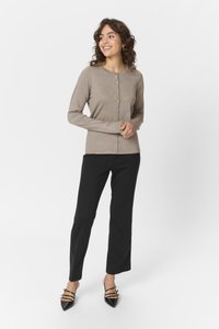Beige geribbelde cardigan met een ronde halslijn, voor knoopsluiting en lange mouwen; gecombineerd met zwarte rechte broek en zwarte hakken.