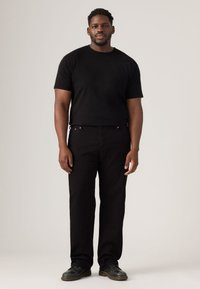 Black T-shirt and black straight-leg pants made of denim, featuring subtle stitching details and a relaxed fit. Footwear is black.