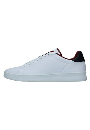 Zapatilla blanca con parte superior de sintético suave, puntera redonda, suela plana blanca y acentos color marrón en el talón y la lengüeta. Logo estampado en el lateral.