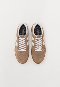Wildledersneaker in einem hellbraunen Farbton mit weißen Akzenten, featuring einer runden Zehenpartie, Schnürdesign und strukturierten Details im Obermaterial.