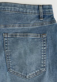 Džínové kalhoty ve světle modré barvě, s zadní kapsou a kontrastním prošíváním a hladkým povrchem, zvýrazňujícími vybledlý vzhled látky.