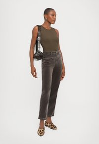 Oliivroheline ilma varrukat bodysuit, hallid corduroy püksid, leopardimustriga slip-on jalanõud ja ümmargune must kott tekstuurse rihmaga.