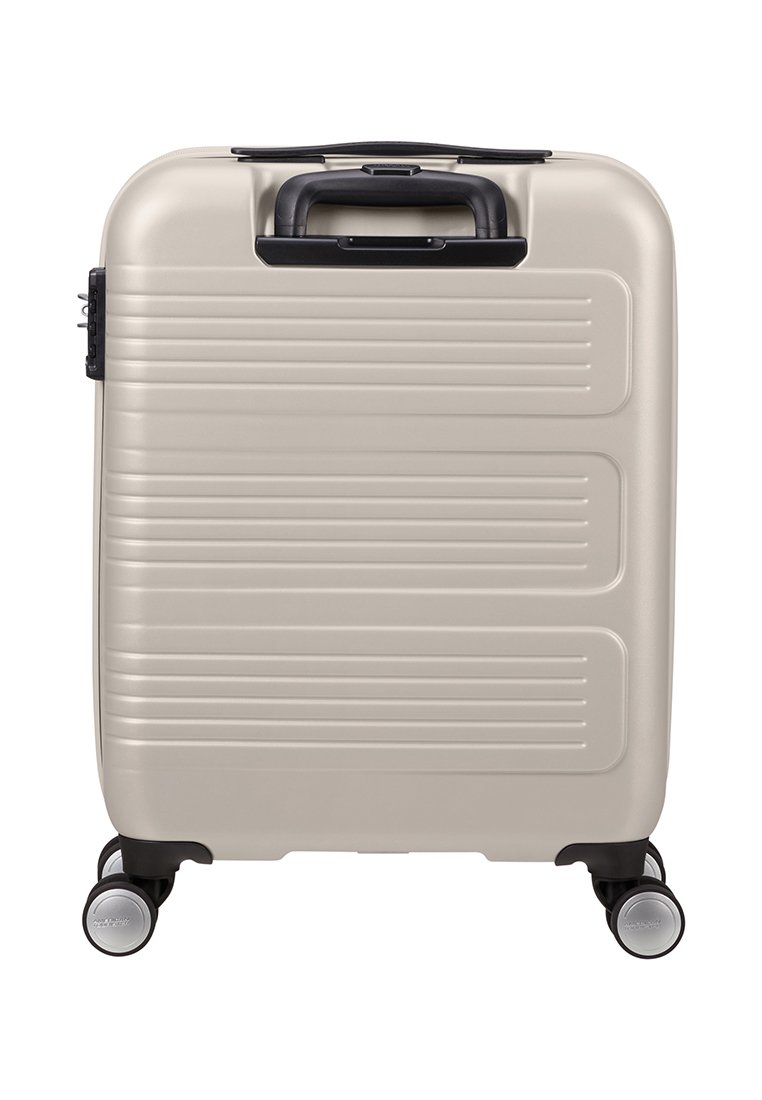 Valise rigide de couleur beige clair avec des rainures horizontales, poignée noire et quatre roues. Texture lisse, forme rectangulaire compacte.