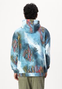 Hooded sweatshirt in soft fabric with a colorful abstract design featuring blue, red, and yellow patterns. Loose fit with elastic waistband.