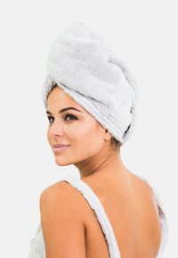 Grå, mjuk mikrofiberhandduk med en vriden turbandesign, säkert fastsatt högst upp. Mjuk textur och slät finish, lämplig för hårtorkning.
