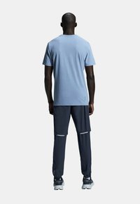Light blue short-sleeve t-shirt and dark blue athletic pants with reflective accents. The fabric appears smooth and lightweight.