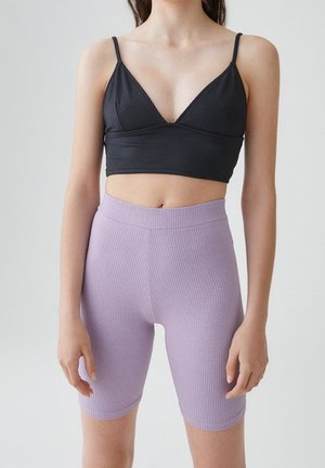 Bralette côtelée noire à fines bretelles associée à un short côtelé lavande taille haute. Les deux présentent une texture lisse et une silhouette ajustée.