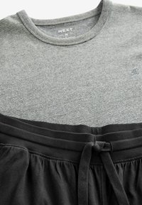 Gråstribet kortærmet T-shirt med rund halsudskæring, parret med sorte shorts med elastisk talje og bindebånd.