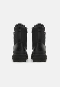 Bottines noires avec une finition en cuir lisse, semelle épaisse et fermeture éclair sur le côté, avec une boucle à l'arrière pour un enfilage facile.
