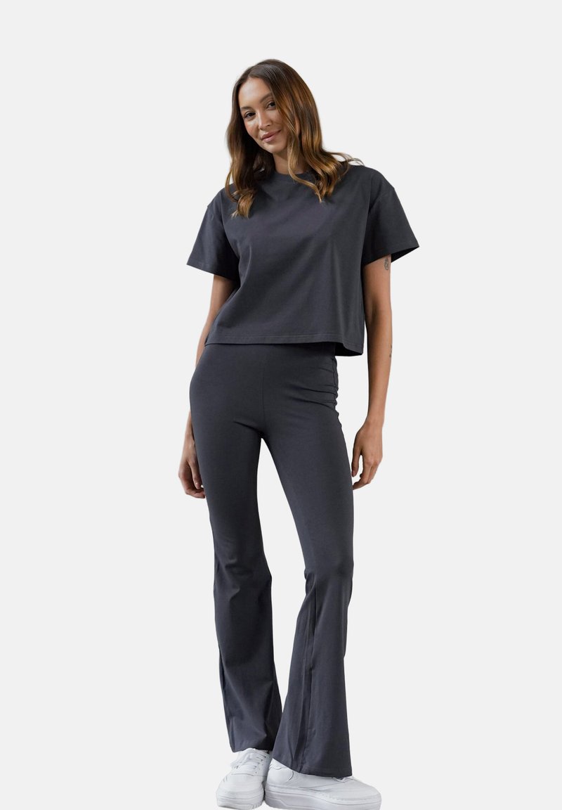 Ciemnoszara zestaw dopasowany składający się z krótkiego t-shirta z krótkimi rękawami i rozszerzających się spodni. Wykonany z gładkiego materiału; zawiera białe sneakersy.