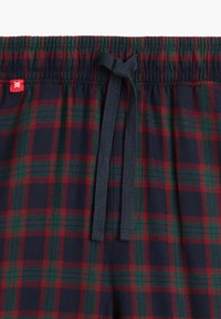 Szorty w kratę z miękkiego materiału w kolorach granatowym, zielonym i czerwonym. Posiadają elastyczny pas z troczkiem oraz małą czerwoną metkę.