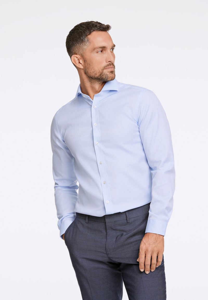  Lichtblauw blouse met lange mouwen en knoopsluiting, met een puntige kraag en rechte pasvorm, gecombineerd met donkergekleurde, gestructureerde broek die een gladde stof laat zien.