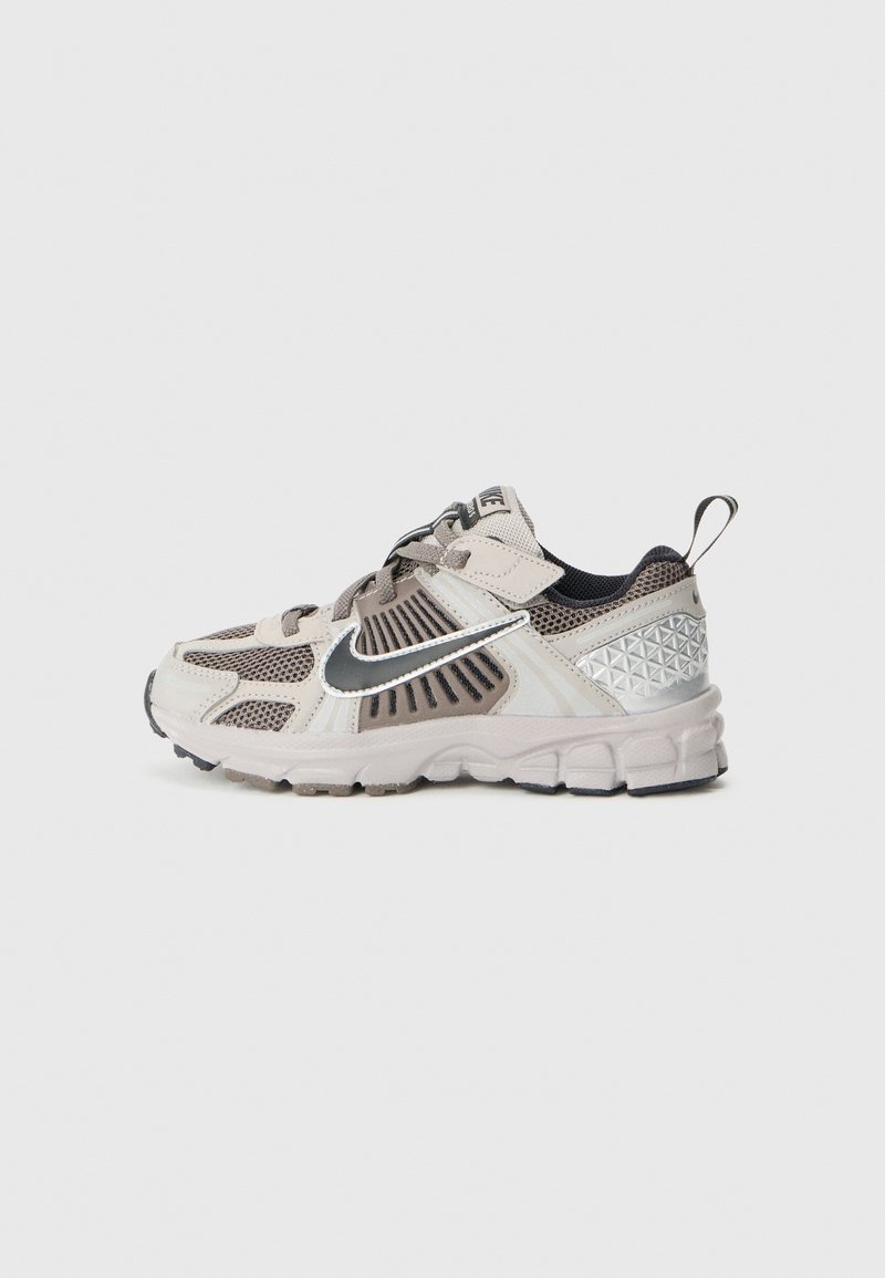 Lightweight athletic shoes in beige and gray, featuring mesh panels, a silver Nike swoosh, and a textured heel with geometric accents.