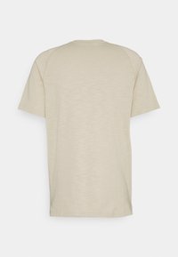 Beżowa koszula z krótkim rękawem i okrągłym dekoltem, o gładkiej fakturze i subtelnych odcieniach kolorystycznych. Brak widocznych wzorów lub akcentów.