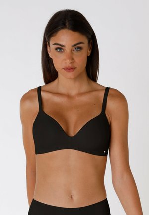 Reggiseno nero con design liscio e sagomato, dotato di spalline regolabili e un logo discreto. Il tessuto sembra morbido ed elastico, offrendo comfort.