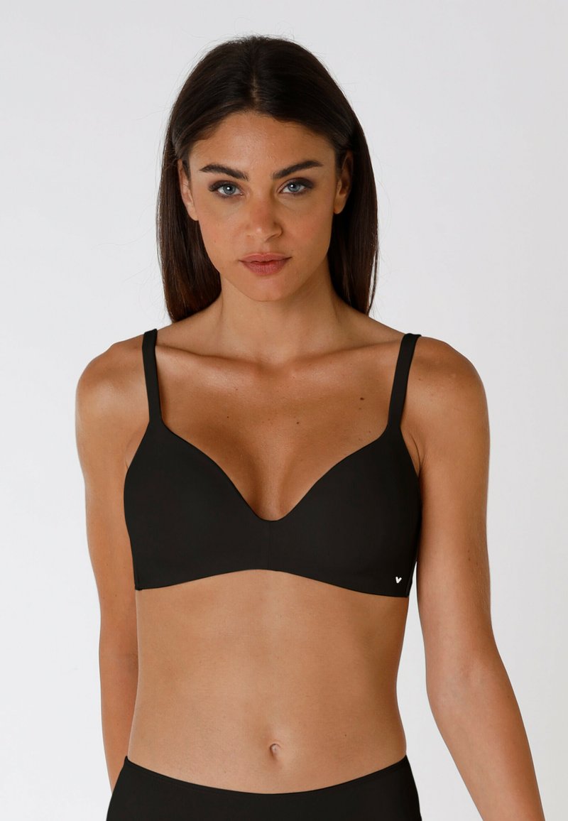 Reggiseno nero con design liscio e sagomato, dotato di spalline regolabili e un logo discreto. Il tessuto sembra morbido ed elastico, offrendo comfort.