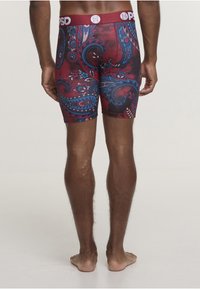 Pánské elastické kraťasy s červenomodrým paisley vzorem. Vyrobené z pružné tkaniny se širokým elastickým pasem s logem.