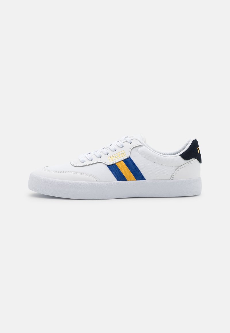 Baskets basses blanches avec bandes latérales bleues et jaunes, lacets blancs et languette de talon bleu marine sur un fond clair uni.