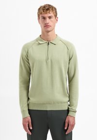 Lichtgroene pullover met een ritssluiting op de kraag, met ribgebreide manchetten en een zoom, gemaakt van zachte gebreide stof. Het ontwerp bevat raglanmouwen.