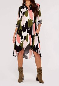 Dlouhé košilové šaty s výrazným abstraktním potiskem v růžové, zelené, černé a bílé barvě, s bočními kapsami a asymetrickým lemem.