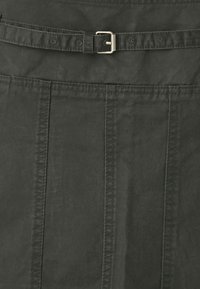 Jupe noire en tissu texturé, dotée d'une taille mi-haute avec une ceinture et de coutures verticales pour plus de détails.